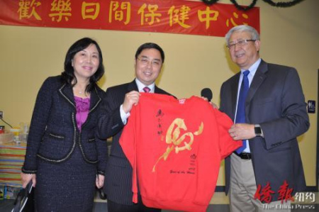 會(huì)長(zhǎng)李志翔代表活動(dòng)中心向公使李克新贈(zèng)送馬年生肖T恤，寓意“馬到成功”（美國(guó)《僑報(bào)》）