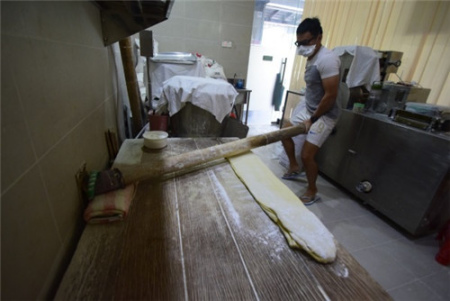 賴銘康示范用祖?zhèn)鲹{面杖搟面，并指手工才能讓面團(tuán)均勻受力，制出的面條才有彈性。(馬來西亞《星洲日報》)