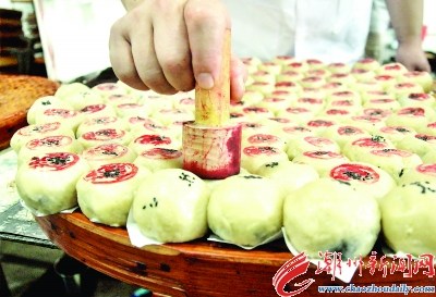 在生餅皮上面綴上黑芝麻，底部墊上白紙片后平整擺放。按傳統(tǒng)慣例，在生餅皮上蓋上鋪號印章。