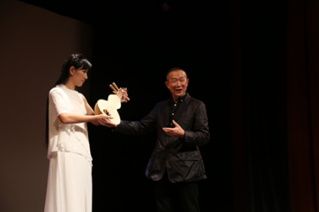 譚盾(右)介紹藉由敦煌古畫而還原出的“反彈琵琶”所用樂(lè)器。(美國(guó)《世界日?qǐng)?bào)》/洪群超 攝) 