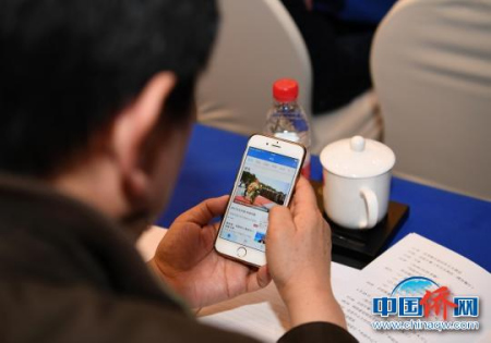 海外華助中心代表用手機(jī)翻閱“僑寶”移動(dòng)客戶端