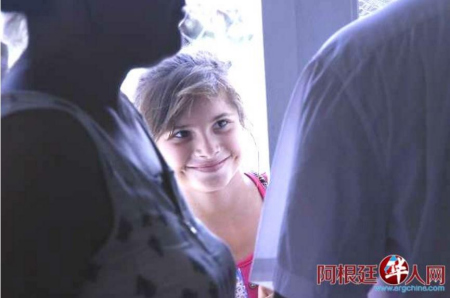 Magali透過人縫偷偷的看著愛心人士，滿心喜悅。（阿根廷華人網(wǎng)）