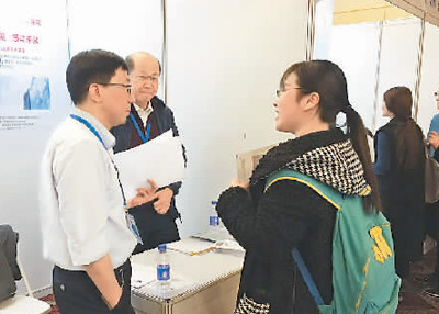 在一家公司的展臺前，一名應(yīng)聘者正在向用人單位咨詢招聘崗位相關(guān)信息。