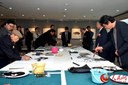 6位中韓藝術家在展廳進行現(xiàn)場即興筆會創(chuàng)作交流。(人民網(wǎng)記者 周軒 攝)
