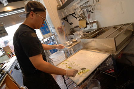 老板容永恒制作石磨腸粉。(美國(guó)《世界日?qǐng)?bào)》/朱澤人 攝)