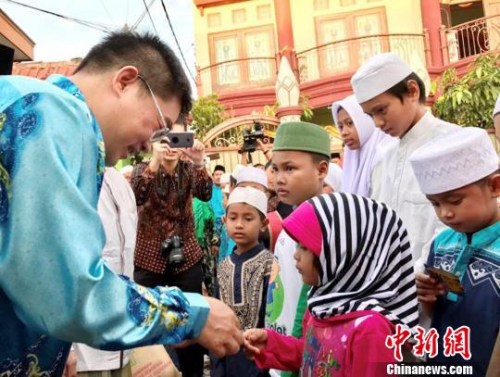 圖為顧景奇向孤兒和貧困兒童發(fā)放禮包?！∏貫榉?攝