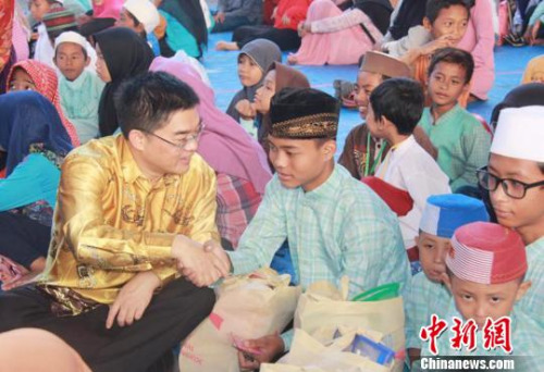 圖為顧景奇向孤兒和貧困兒童發(fā)放禮包。　秦為芬 攝