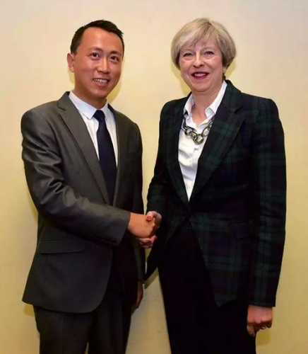 參加2017年英國(guó)大選的華裔候選人何易與英國(guó)首相特雷莎·梅合影。(受訪者供圖)