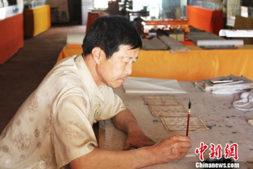 在甘肅敦煌市的一處民俗旅游地——月牙泉小鎮(zhèn)內(nèi)，傅有宏伏案臨摹敦煌漢簡?！⌒煅?攝