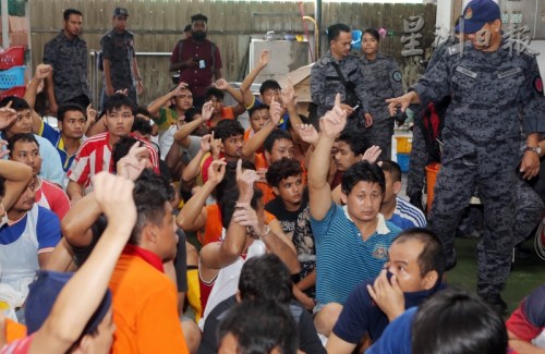 移民局官員詢問是否擁有護(hù)照時，許多外勞舉起手。(馬來西亞《星洲日報》)