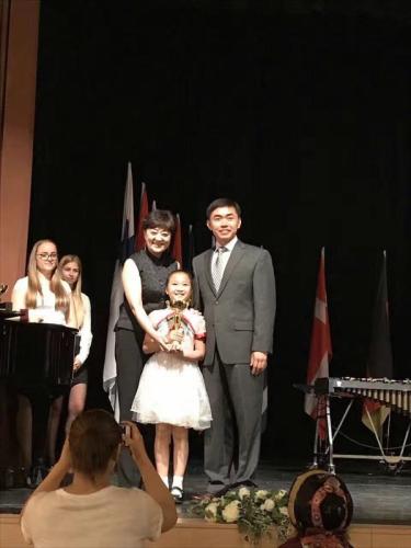 中囯駐匈使館領(lǐng)事部主任李克震(右)向北京電視臺(tái)七色光藝術(shù)團(tuán)指揮韓曉彤、合唱團(tuán)代表頒發(fā)金獎(jiǎng)。(匈牙利《歐洲論壇》)