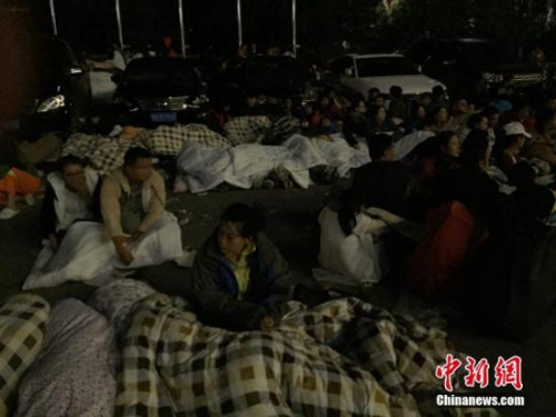 圖為九寨溝景區(qū)內(nèi)，許多游客不敢繼續(xù)待在酒店內(nèi)，裹著厚衣服和毛毯來(lái)到街上席地而睡。 徐廣 攝