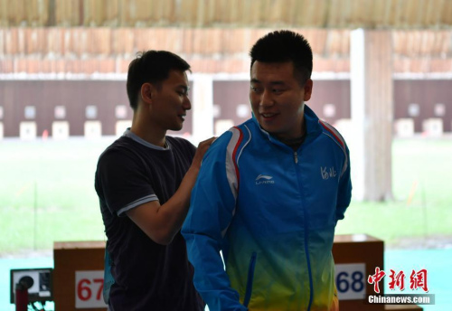 8月28日，天津團(tuán)泊體育中心射擊館，美籍華人選手石晶參加第十三屆全國運(yùn)動(dòng)會(huì)男子50米手槍預(yù)賽，位列第18名。圖為石晶（左一）幫助龐偉整理背標(biāo)。 <a target='_blank' >中新社</a>記者 翟羽佳 攝