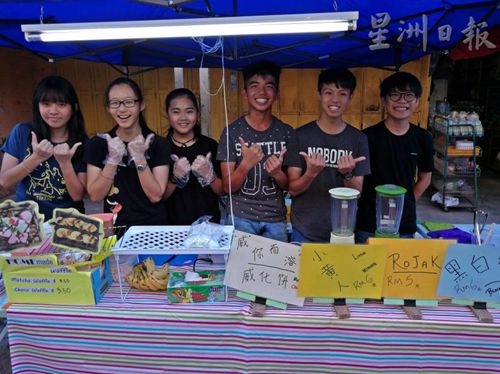 羅俊偉(右二)和同學(xué)們利用學(xué)校假期擺攤做生意，部份所賺的錢將捐給慈善團(tuán)體，愛心滿滿。(圖：星洲日報(bào)) 