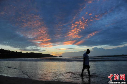 資料圖：普吉島被譽(yù)為泰國的“珍珠”，這里擁有迷人的風(fēng)光和豐富的旅游資源，每年都吸引眾多游客來此休閑觀光。圖為一名游客從海灘上走過。洪堅(jiān)鵬 攝