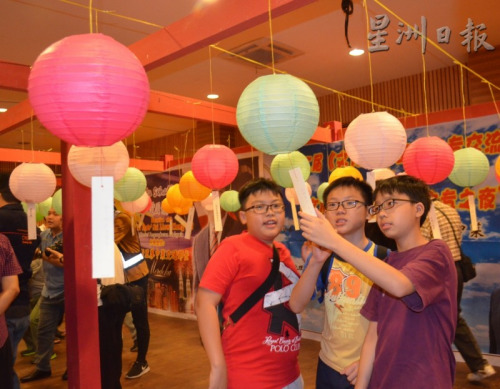 青少年對猜燈謎產(chǎn)生了興趣，共同思考找答案。（馬來西亞《星洲日報》）