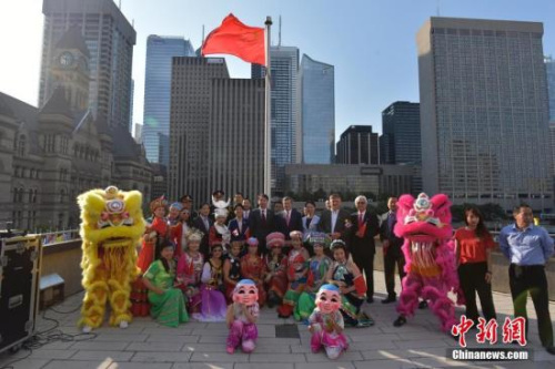 當?shù)貢r間9月27日上午，中國駐多倫多總領事館在多倫多市政廳舉行升旗儀式，慶祝中華人民共和國成立68周年。中國駐多倫多總領事何煒夫婦、多倫多市長莊德利（John Tory）與多位嘉賓、華僑華人代表等在五星紅旗下合影。 中國駐多倫多總領館 供圖
