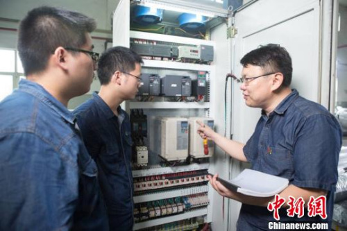 鄧建軍和同事們探討設(shè)備情況。 江蘇常州黑牡丹(集團(tuán))股份有限公司供圖。