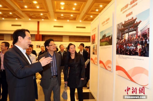 10月13日，國務(wù)院僑務(wù)辦公室副主任譚天星（左）在北京參觀“服務(wù)僑胞·情暖僑心”——迎接黨的十九大主題攝影展，該展覽由國務(wù)院僑務(wù)辦公室主辦，中國新聞社圖片網(wǎng)絡(luò)中心承辦。 <a target='_blank' >中新社</a>記者 張宇 攝