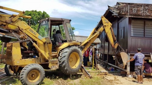 人力不足，丹土生華裔協(xié)會(huì)出動(dòng)挖泥車助力。（馬來西亞《星洲日?qǐng)?bào)》） 葉興再（右）發(fā)號(hào)司令，和村民各就各位，移動(dòng)房子。（馬來西亞《星洲日?qǐng)?bào)》）
