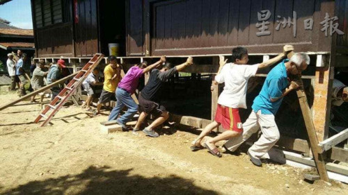 村民守望相助，重現(xiàn)人力搬動(dòng)房子的風(fēng)俗。（馬來西亞《星洲日?qǐng)?bào)》）