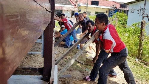 葉興再（右）發(fā)號(hào)司令，和村民各就各位，移動(dòng)房子。（馬來西亞《星洲日?qǐng)?bào)》）