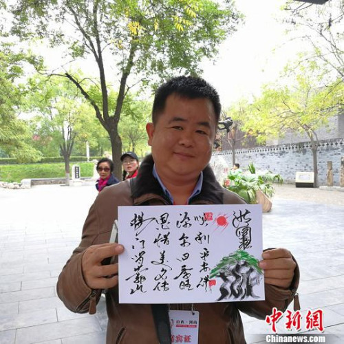 緬甸大其力大華學(xué)校負(fù)責(zé)人楊恩源在洪洞大槐樹景區(qū)向記者展示自己姓氏的文創(chuàng)產(chǎn)品。　楊杰英 攝