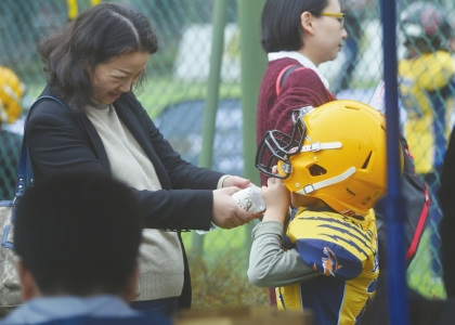訓(xùn)練場邊的家長給自己的孩子喂水。