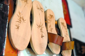 吳伯親手在木屐上鉻畫。