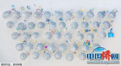 “相機攝”江蘇連云港市蘇馬灣海濱浴場，游客們在遮陽傘下悠閑休息。