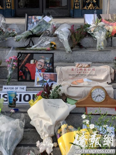 臺(tái)階上擺放著鮮花和李市長(zhǎng)喜愛(ài)的金門(mén)餅家簽語(yǔ)餅和寫(xiě)著紀(jì)念語(yǔ)的T恤。(僑報(bào)記者陳勇青攝)