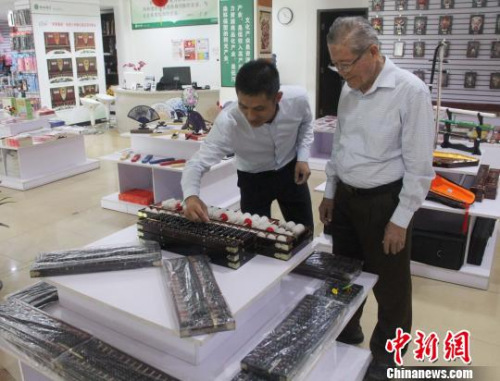 圖為王林(左)在演示算盤?！×钟纻?攝