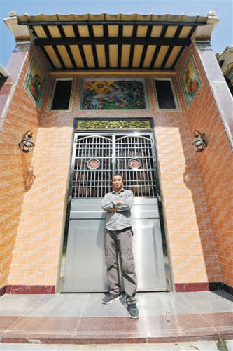 潘先良與其繪制的民居壁畫合影。 海南日報記者 袁琛 攝