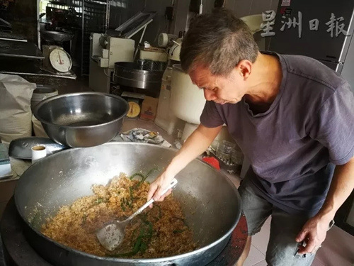 王振隆以大鍋翻炒香噴噴的椰絲佐料。(馬來西亞《星洲日報(bào)》記者/李慧婷 攝)