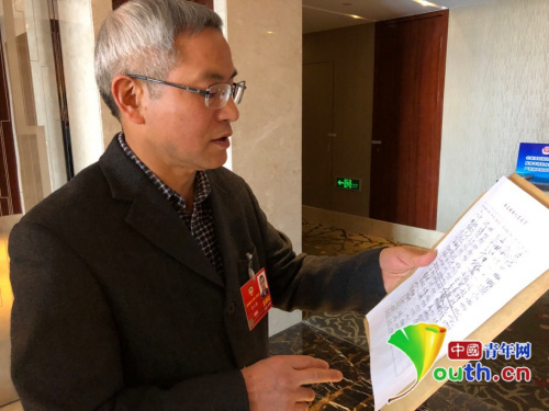 　全國政協(xié)委員賀云翱發(fā)起這份聯(lián)合提案，圖為提案最終遞交前他向記者介紹簽名情況。中國青年網(wǎng)記者 吳楚 攝