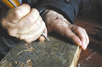 　圖②為任鶴林正在雕刻年畫(huà)印版。