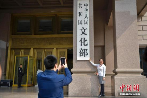 3月13日下午，文化部員工在文化部門(mén)前拍照留念。當(dāng)日，《國(guó)務(wù)院機(jī)構(gòu)改革方案》提請(qǐng)十三屆全國(guó)人大一次會(huì)議審議。方案提出，組建文化和旅游部，不再保留文化部、國(guó)家旅游局。 <a target='_blank' >中新社</a>記者 駱云飛 攝