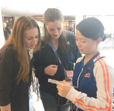 　護(hù)旗手汪美侖(右一)在用自己制作的貴州風(fēng)光明信片介紹家鄉(xiāng)。 