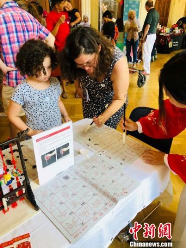 當(dāng)?shù)貢r(shí)間8月4日，美國(guó)首都華盛頓的美國(guó)革命女兒博物館舉辦“2018世界博覽會(huì)”(World's Fair)。華盛頓亞洲文化中心、華加視頻作為首個(gè)受邀展示中華傳統(tǒng)文化的合作方，為活動(dòng)現(xiàn)場(chǎng)增添了濃郁的東方色彩。圖為美國(guó)觀眾認(rèn)真學(xué)習(xí)中國(guó)書(shū)法技巧?！ochelle Wang　攝