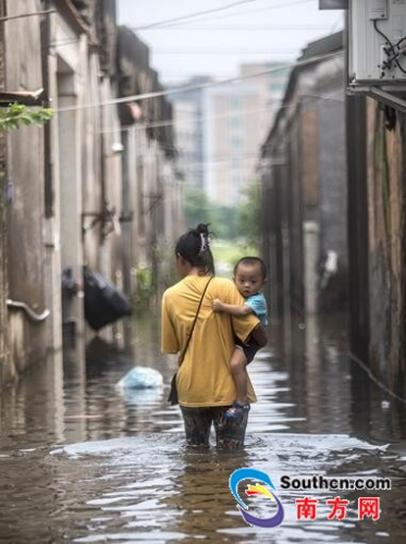 9月2日，陳店鎮(zhèn)北溝村，水位開始退去，一名大人帶著孩子蹚水回家。南方網(wǎng)全媒體記者 張由瓊 實習(xí)生 徐杰 攝
