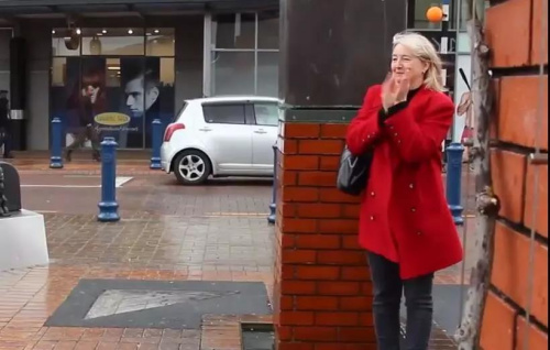 一位冒著風(fēng)雨觀看阿姨們廣場舞的新西蘭女士。(新西蘭天維網(wǎng))