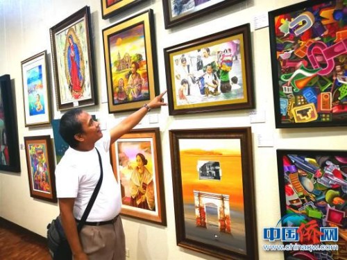 菲律賓畫家向記者介紹自己的作品?！￡P(guān)向東 攝