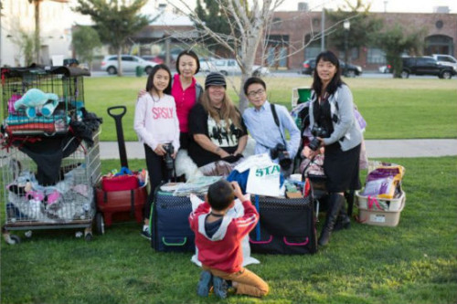 周女士(右)和兒子(右二)一起參加為流浪女(中)捐送衣物的活動(dòng)。(美國(guó)《僑報(bào)》/周女士提供)