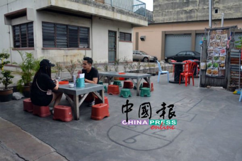 在祖屋前，與三兩好友蹲坐小凳存吃著鮮蛤，別具風(fēng)味。(馬來西亞《中國報》記者 趙詩綺 攝)