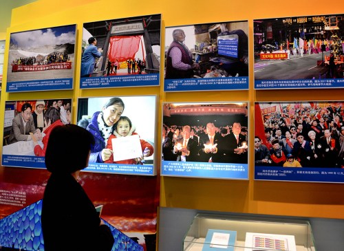 一位參觀者在“海外僑胞心系祖國(guó) 助力改革開(kāi)放”展廳，觀看“2005年5月，第三屆世界華僑華人社團(tuán)聯(lián)誼大會(huì)與會(huì)代表舉行燭光祈愿儀式，表達(dá)‘反獨(dú)促統(tǒng)’心聲”等展覽照片。（《芝加哥華語(yǔ)論壇》/張大衛(wèi) 攝）