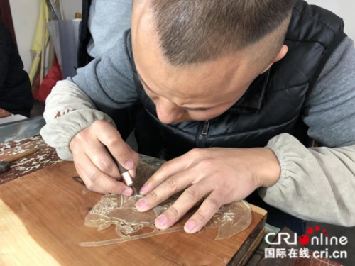 皮影匠人用華州皮影獨(dú)一無二的“推皮走刀法”雕刻。攝影：張捷