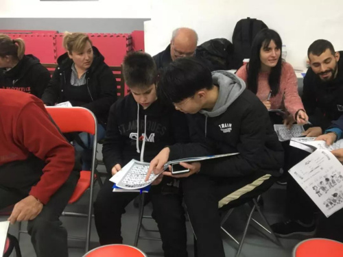 志愿者黃承輝(前排右一)輔導(dǎo)學(xué)員漢語拼音。(《歐洲時報》/蘇珊娜 攝)