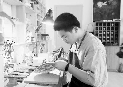 王建榕在專心致志地鋦瓷。