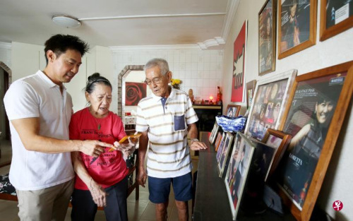 陳之財(左一)與父親陳秋福(右一)及母親吳麗群一起看家里的舊照片。(新加坡《聯(lián)合早報》/龍國雄 攝)