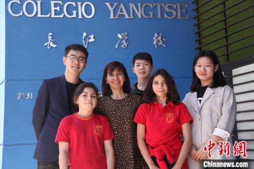 圖為11月6日，長(zhǎng)江學(xué)校校長(zhǎng)羅哈斯(Marcela Rojas Cantillana，左三)、國(guó)家漢辦駐智利漢語(yǔ)教師志愿者管理教師劉昌(左一)、長(zhǎng)江學(xué)校中文老師李媛媛(右)與學(xué)生們?cè)趯W(xué)校門前合影。<a target='_blank' >中新社</a>記者 余瑞冬 攝